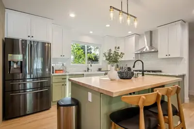 a kitchen with white cabinets and a stainless steel refrigerator at Lake Balboa Hideaway in Los Angeles