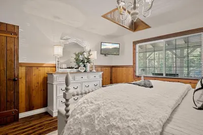 a bedroom with a bed and a dresser and a window at Eureka Ranch Designer Cabin in Big Bear Lake