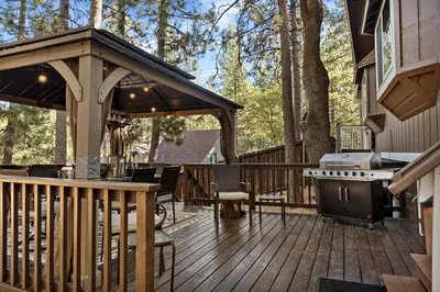 a wooden deck with a grill on a house at Eureka Ranch Designer Cabin in Big Bear Lake