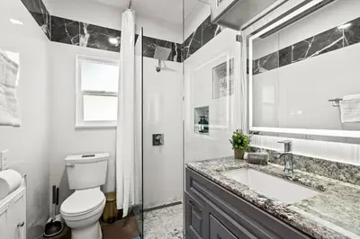 a bathroom with a toilet and a sink and a mirror at 2BR Luxury Getaway Mins to Beach Arcade & Games in Manhattan Beach