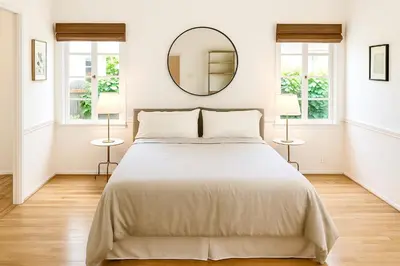 a white bedroom with a large bed and a mirror at Enchanting Hollywood Hills Oasis with Tree-Top Views, Serene Outdoor Living Room, Zen Garden, Free Attached Garage, Sleeps 6, in LA's Most Desirable, Central, Serene Canyon Neighborhood, and Only 2 Minutes to Hollywood Boulevard in Los Angeles