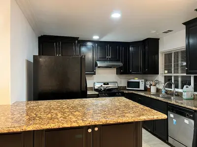 a kitchen with black cabinets and a granite counter top at Near Disney,college,sunset beach ,airport in Norwalk