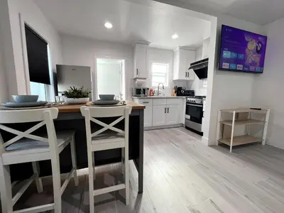 a kitchen with a table and two white stools at Gated & Morden 1bed1bath house3367 in Baldwin Park