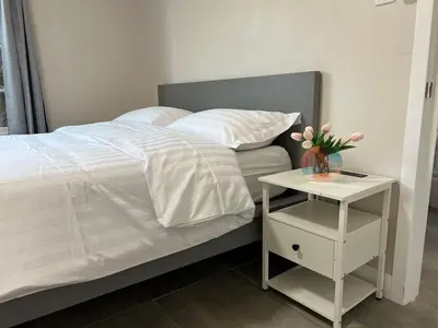 a bed with a side table with a vase of flowers on it at Fully remoded 1B1B Home in baldwin Park3369A in Baldwin Park