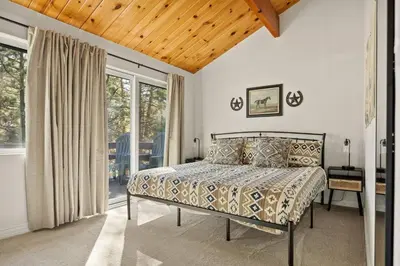 a bedroom with a bed and a large window at Cowboy Cabin with Lake Views in Big Bear Lake