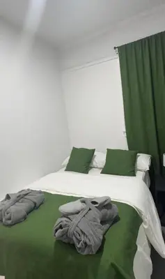 a bed with green and white sheets and towels on it at Naryn Guest house in Los Angeles