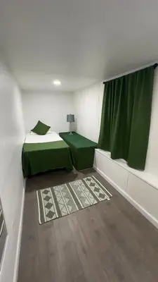 a room with two beds and a green curtain at Naryn Guest house in Los Angeles