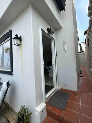 a white house with a door with a mirror at Manhattan Beach Beachfront Charming On The Strand in Manhattan Beach
