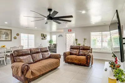a living room with two leather chairs and a ceiling fan at 1 Mi to Rabobank Arena Home with Gazebo! in Bakersfield