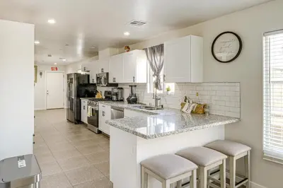 a kitchen with white cabinets and a counter with stools at 1 Mi to Rabobank Arena Home with Gazebo! in Bakersfield