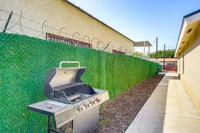 a barbecue grill sitting next to a green fence at 1 Mi to Rabobank Arena Home with Gazebo! in Bakersfield
