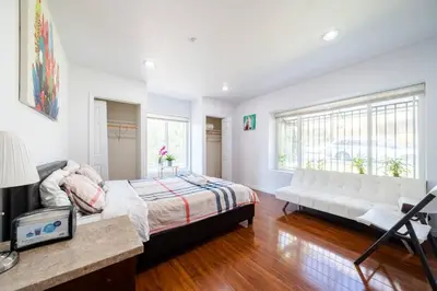 a bedroom with a bed and a white couch at 40 ppl 2 houses 13 Bedrooms btw Disney Hollywd in Monterey Park