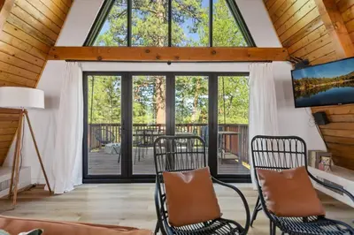 a living room with two chairs and a large window at Midnight Chalet Big Bear Lake in Big Bear Lake