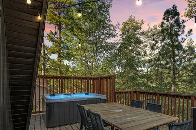 a deck with a wooden table and a hot tub at Midnight Chalet Big Bear Lake in Big Bear Lake