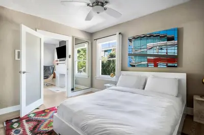 a bedroom with a large white bed and two windows at Venice Gem Private Beach Bungalow in Los Angeles