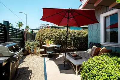 a patio with a table and a red umbrella at Venice Gem Private Beach Bungalow in Los Angeles