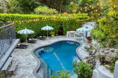 a swimming pool in a yard with umbrellas at Laurel Canyon Classic Hollywood Residence With Pool in Los Angeles