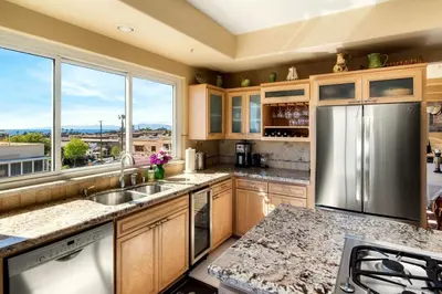 a kitchen with a stainless steel refrigerator and a large window at Oceanview Coastal Retreat in Redondo Beach in Redondo Beach