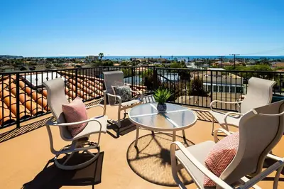 a patio with chairs and a table on a balcony at Oceanview Coastal Retreat in Redondo Beach in Redondo Beach
