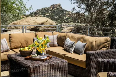 a brown couch sitting on a patio with a table at Retreat to the Rocks Historic Film And Music Getaway in Chatsworth Lake Manor