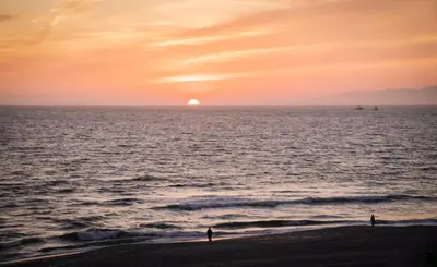 two people standing on the beach watching the sunset at New The Triton Manhattan Beachfront Escape in Manhattan Beach