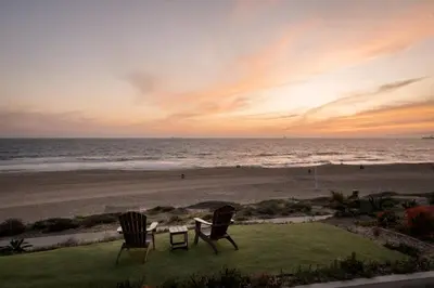 two chairs and a table on the beach at sunset at New The Triton Manhattan Beachfront Escape in Manhattan Beach