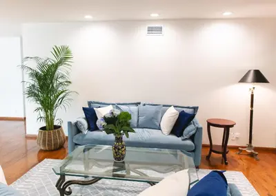 a living room with a blue couch and a glass table at Bella Villa near Beverly Hills Amazing City view and hot tub in Los Angeles