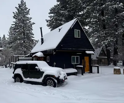 a black truck parked in front of a house with snow at The Honey Bear Cabin Jacuzzi EV Friendly Renovated in Green Valley Lake
