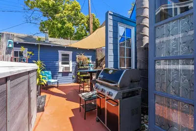 a patio with a grill and a blue house at Spa, Parking, King Bd, Desk, 7 Min Walk to Beach in Long Beach