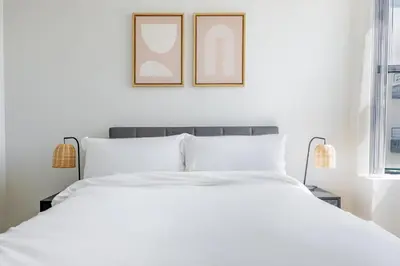 a bedroom with a white bed with two pictures on the wall at Blueground Venice pool wd nr beach LAX-1329 in Los Angeles