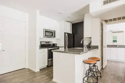 a kitchen with white cabinets and a counter with stools at Blueground Burbank pool bbq nr studios LAX-1321 in Los Angeles