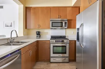 a kitchen with stainless steel appliances and wooden cabinets at Blueground Playa Vista pool AC nr beach LAX-1353 in Los Angeles