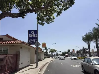 a street with cars driving down a street with a motel at World Motel in Lynwood