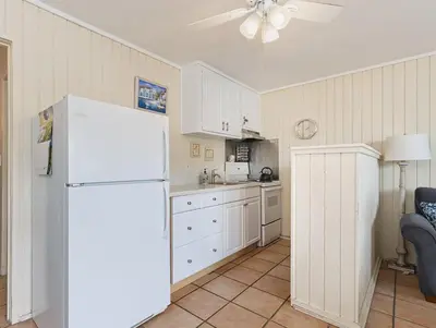 a kitchen with white cabinets and a white refrigerator at Beach Condo with Private Patio #133 in Carpinteria