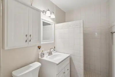 a white bathroom with a sink and a mirror at Beach Condo with Private Patio #133 in Carpinteria
