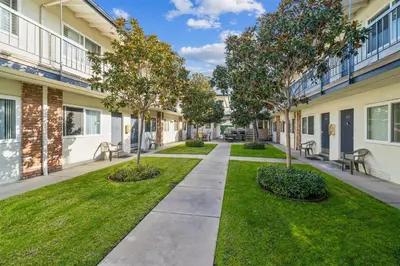 a walkway between two buildings with trees and grass at Lovely 1 Bed Beach Condo #128 in Carpinteria
