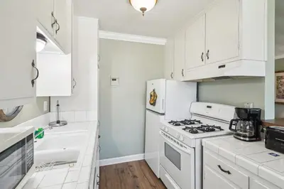 a kitchen with white cabinets and a stove top oven at 1 Bed Beach Condo #131 in Carpinteria