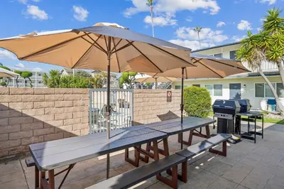 two picnic tables with an umbrella and a grill at Beautiful 2 Bed Beach Condo #201 in Carpinteria