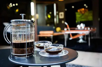 a container of coffee sitting on a table with two glasses at NEW Modern Oasis off Melrose - Rooftop - Pool in Los Angeles