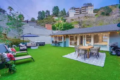 a backyard with green grass and a table and chairs at Hollywood Hills Retreat - Private GYM & STEAM ROOM in Los Angeles