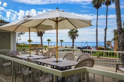 a table with an umbrella on a deck with the beach at 4980 Sandyland Road #215 in Carpinteria