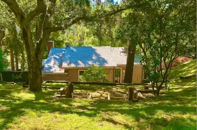 a house with a blue roof in a yard with trees at Hollywood Hills Spa Retreat Oasis with Tree Top Views, Private Jacuzzi Style Tub, Steam Room, Magical Half Acre Acre Garden and Patio, Free Parking for 2 cars, in LA's most Serene, Central Desirable Area in Los Angeles