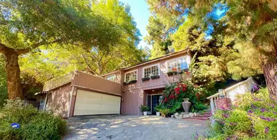 a house with a garage and a tree at Hollywood Hills Spa Retreat Oasis with Tree Top Views, Private Jacuzzi Style Tub, Steam Room, Magical Half Acre Acre Garden and Patio, Free Parking for 2 cars, in LA's most Serene, Central Desirable Area in Los Angeles
