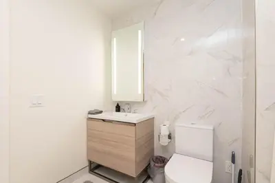 a white bathroom with a sink and a toilet at Snug 3BR HighRise with Pool, Spa & Rooftop Views in Los Angeles