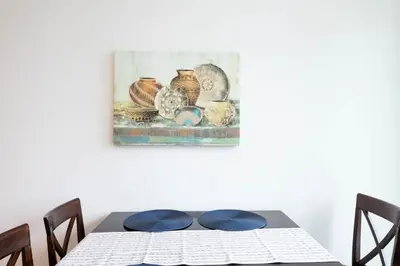 a dining room table with a painting on the wall at Snug 3BR HighRise with Pool, Spa & Rooftop Views in Los Angeles