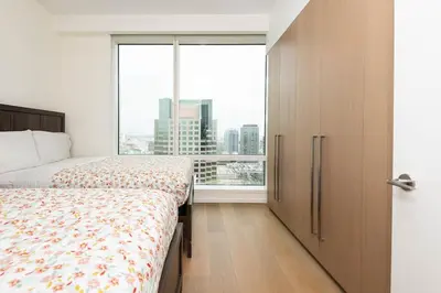 a bedroom with two beds and a large window at Snug 3BR HighRise with Pool, Spa & Rooftop Views in Los Angeles