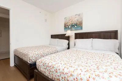 a bedroom with two beds and a painting on the wall at Snug 3BR HighRise with Pool, Spa & Rooftop Views in Los Angeles