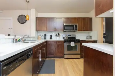 a kitchen with wooden cabinets and stainless steel appliances at Cozy 2BR Apt in Downtown LA with Pool & Hot Tub in Los Angeles
