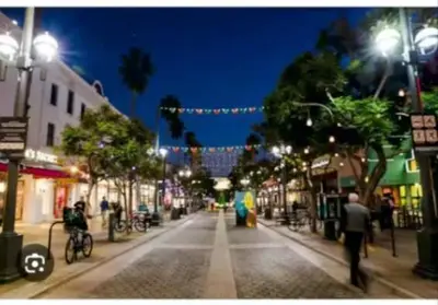 a city street at night with people walking down the street at Walk to Santa Monica Beach Pier Boardwalk Venice in Los Angeles