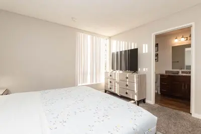 a white bedroom with a bed and a television at 2BR Hollywood Apt with Rooftop Pool & Stunning Views in Los Angeles
